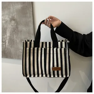 Detail of black and white striped canvas tote with front pockets and fashion leather label
