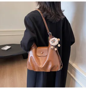 Detail view of brown faux leather tote bag with stylish plush lion keychain accessory