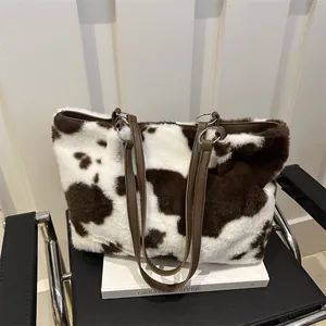 Dettaglio della borsa tote in peluche con stampa mucca, manici in pelle e morbida pelliccia