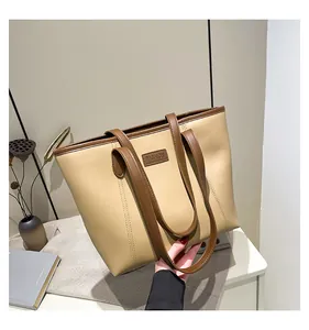 Detail of beige tote bag with brown leather trim and fashion logo embossing