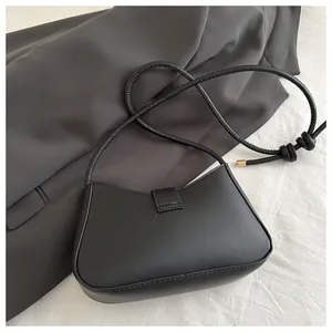 Détail du sac croissant noir minimaliste avec poignée nouée et embouts en métal doré