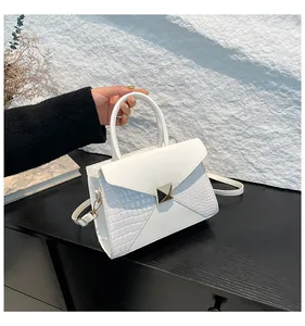 Détail d'un sac à main blanc avec boucle dorée et finitions en cuir texture crocodile