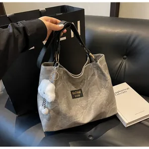 Détail du sac cabas en toile grise avec anses en cuir noir et breloque pelucheuse