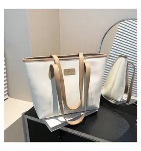 Detailed close-up of cream-colored tote bag with khaki leather trim and fashion embossing