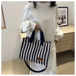 Close-up of navy blue and white striped tote bag featuring a brown leather fashion tag