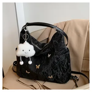 Détail du sac à main noir plissé avec breloques papillon en métal et pendentif nuage en peluche