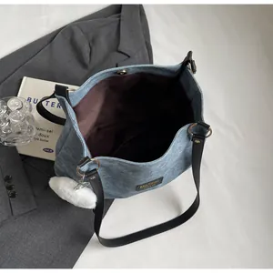 Détail d'un sac cabas en denim bleu clair avec breloque peluche et doublure spacieuse