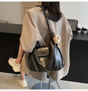 Black matte leather tote bag worn by a model in a professional lifestyle setting