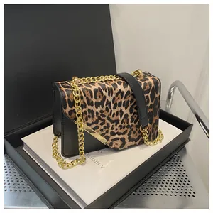 Dettaglio borsa leopardata con tracolla a catena dorata su confezione regalo