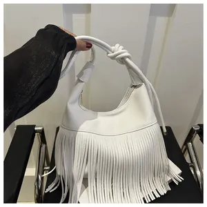 Detalle del bolso hobo blanco de cuero con flecos largos y un asa de cuerda trenzada