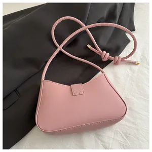 Détail du sac croissant rose montrant la bandoulière tressée nouée et accents dorés