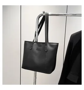 Detail view of black faux leather tote bag with FASHION patch on a metal stand