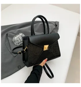 Détail du sac bandoulière noir avec texture crocodile et boucle pyramide dorée chic