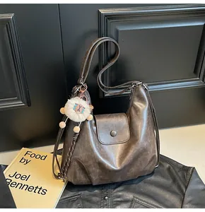 Detail of vintage brown leather hobo bag with soft texture and white sheep charm