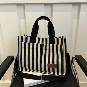 Large black and white striped canvas tote bag with brown leather label and shoulder strap