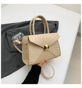 Détail du sac à rabat beige en cuir lisse et texture crocodile avec boucle dorée