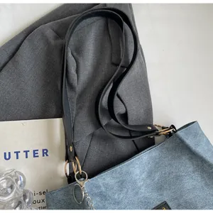 Détail du sac cabas en daim bleu avec large bandoulière noire et chaîne en métal argenté
