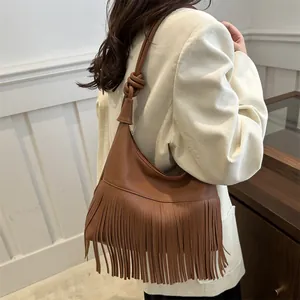 Bolso de hombro en cuero marrón con flecos largos y correa con nudos puesto en modelo