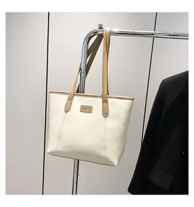 Detail of cream tote bag featuring a leather FASHION label and slim khaki straps