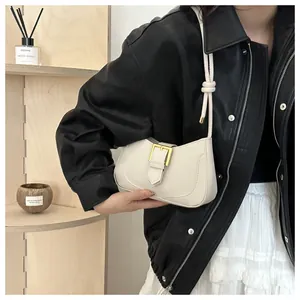 Gros plan du sac croissant crème avec boucle dorée et bandoulière à nœuds