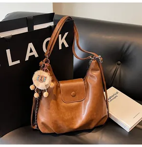 Detailed view of a brown vintage tote bag with a magnetic clasp and plush charm accessory