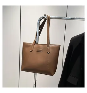 Detailed view of brown leather tote bag with Fashion tag hanging by a black suit