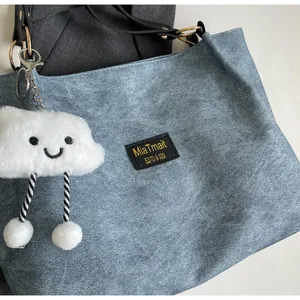 Détail du sac cabas bleu clair en daim avec anse noire et charme nuage peluche
