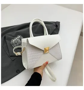 Détail du sac à main blanc motif crocodile avec boucle en métal doré et doubles poignées