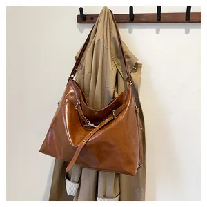 Detail einer braunen Vintage-Einkaufstasche an einem Haken neben einem Trenchcoat