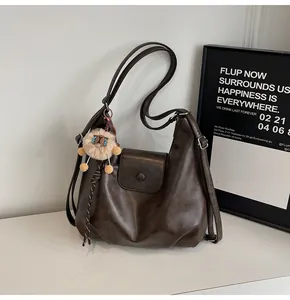 Detail of dark brown leather tote featuring a magnetic flap and cute plush pendant