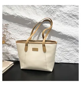 Close-up of cream tote bag featuring brown leather trim and a central FASHION patch