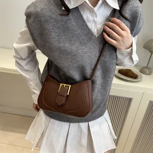 Sac bandoulière vintage marron en forme de croissant avec boucle dorée et décor épuré