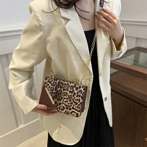 Borsa a tracolla leopardata alla moda con catena dorata indossata da una modella in abito