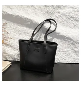 Close-up of a black tote bag featuring a Fashion leather patch and minimalist stitching