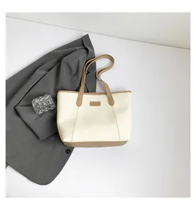 Detail of minimalist cream and brown leather tote bag with FASHION logo tag and stitching