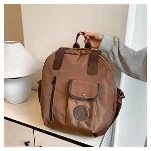 Detailed view of dark brown nylon backpack featuring a metal buckle flap and side pockets