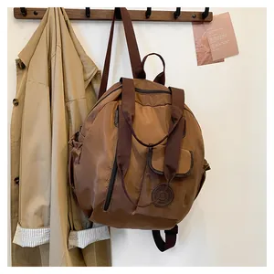 Detailed view of a brown nylon circular travel backpack with functional external pockets