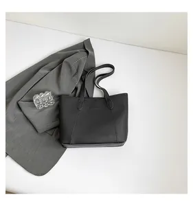 Detailed view of black matte tote bag with Fashion label on elegant grey blazer background