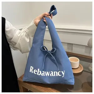 Detail of blue canvas tote bag featuring Rebawancy print and decorative ribbon bow