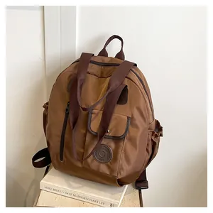 Detail view of water-resistant nylon fabric and leather logo on caramel travel backpack