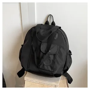 Detail of waterproof black nylon backpack showing top handle and flap pockets