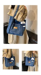 Detail view of large denim tote bag with leather logo patch and plush cloud charm