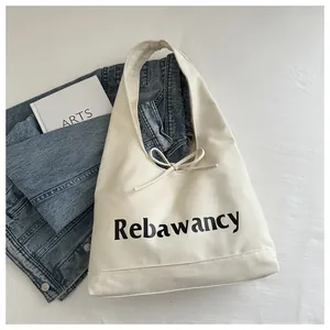 Top view of cream canvas tote bag with bow detail and Rebawancy text on white fabric