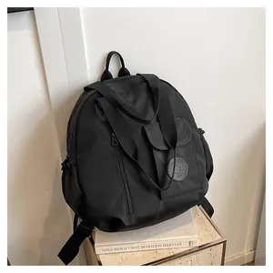 Close-up of black multifunctional nylon travel backpack with round logo and front pocket