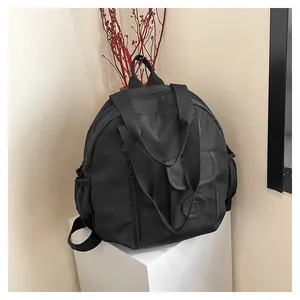 Detail of black waterproof nylon multi-pocket travel bag on a white display stand