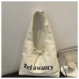 Detail of cream canvas hobo bag featuring black letter print and bow tie closure