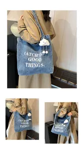 Detail of blue denim tote bag with white text print and a soft cloud plush pendant