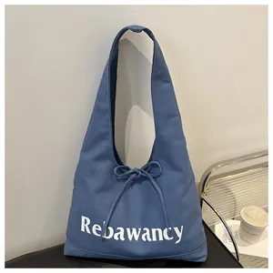 Detail of blue canvas tote bag with Rebawancy text and bow tie knot decoration
