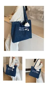 Detail of blue denim tote bag with Less Mondays More Sundays embroidery and cloud charm