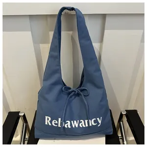 Close-up of blue canvas tote bag with Rebawancy text and decorative bow detail